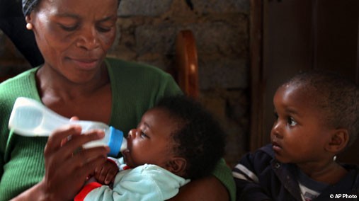 A mother feeds her two-month-old baby a bottle of formula, as her second youngest son watches at their home in Soweto, South Africa, March 8, 2007. [AP File Photo]