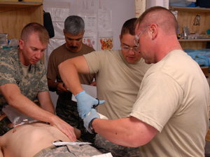 CPT Charles Day (left), battalion surgeon of the 2nd-87th Infantry, supervises as medics treat a simulated injury during emergency medical technician recertification training in Afghanistan.