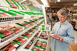 Photo: A woman looking at a package of meat in a grocery store.  Link to photo information