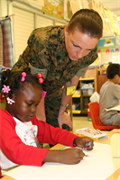 Staff Sgt. Sara Fine asks Allaija Williams, 5 about her art. Fine volunteers teaching art to students at Webling Gus Elementary School, Honolulu, through the Adopt-A-School program.