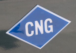 Photo of a blue, diamond-shaped decal on a vehicle, indicating it runs on compressed natural gas. The decal reads, CNG.