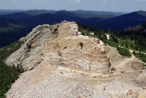 One of the Black Hills being carved into a massive statute of Crazy Horse riding into battle on his horse Inyan. Click through for image source.