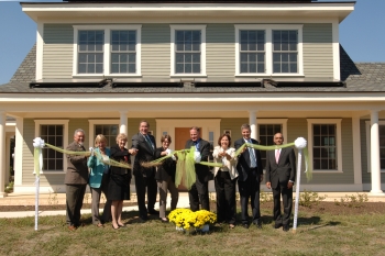 Grass seed falls from a ribbon as officials celebrate the opening of the Net-Zero Residential Test Facility on NIST’s Gaithersburg, Md., campus.