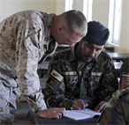 Capt. Jason Thomas helps Afghan National Army Sgt. Najibullah Qabel with forming sentences during an advanced English class at Camp Dwyer Feb 16. The class is part of an exchange between the 1st Brigade, 215 Corps and the Marine Corps brigade advisor team. The course lasts four weeks and is taught five days a week. 