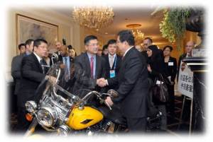 Shaking hands over a Harley-Davidson Softail are China’s Minister of Commerce, Chen Deming (right), and former Secretary of Commerce, current U.S. Ambassador to China, Gary Locke (center) (Photo Commerce)
