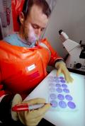 Man in an air tight suit looking at samples on a light board