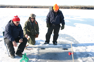 Three friends out on a cold day ice fishing at Lake Yankton.