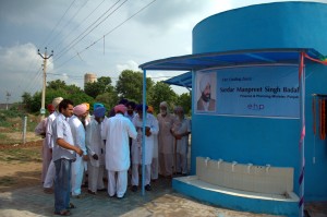 Group of people surrounding small water treatment facility at Healthpoint Services Global India Ltd.