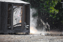 Marines, with 2nd Combat Engineering Battalion, 2nd Marine Division, brace in line behind a blast blanket while a charge is set off. The blanket serves as a shield between flying debris and Marines who were standing just feet away from the door after placing explosives on it. Instructors at Engineer Training Area 3 and Marines worked together, January 10, so Marines could learn basic urban breaching skills for their scheduled deployment to Afghanistan. The main focus for Marines after getting down all the basics was learning how to use what’s around them for explosive charges, said Cpl. Rollie Lemons, of Austin, Texs, sapper instructor with 2nd CEB.