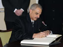 Attorney General Holder signs the guest book at the Auschwitz-Birkenau Memorial and State Museum.