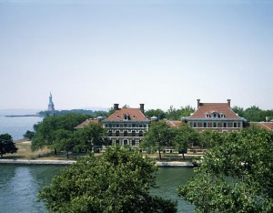 The Statue of Liberty is an ever-present symbol in the distance, beyond Ellis Island's original administration building, right, and hospital.  (Carol M. Highsmith)