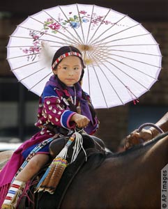 Young American Indian girl on horseback, holding parasol. (AP Images)