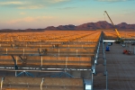 Installing a concentrating solar power system in Gila Bend, Arizona. The curved  mirrors are tilted toward the sun, focusing sunlight on tubes that run the length of the mirrors. The reflected sunlight heats a fluid flowing through the tubes. The hot fluid then is used to boil water in a conventional steam-turbine generator to produce electricity. | Photo by Dennis Schroeder. 