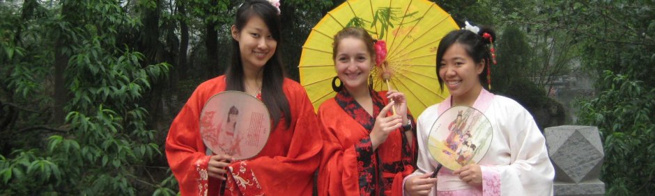 Group of women in kimonos holding up an umbrella and fans