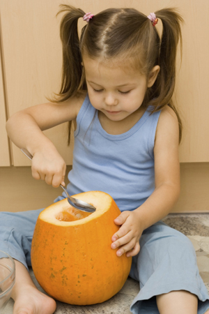 Girl scooping pumpkin with a spoon