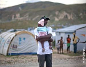 Man holding baby in Haitian tent camp (AP Images)