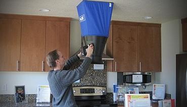 Photo of a man holding a flow hood to the ceiling.