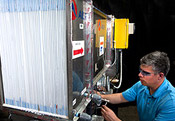 Photo of an engineer working on a first generation prototype desiccant-enhanced evaporative air conditioner that links to a fact sheet about NREL's Energy-Saving Technology for Air Conditioning Cuts Peak Power Loads Without Using Harmful Refrigerants.