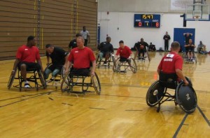 The Army wheelchair basketball team moves the ball down the court in their game against the Marines.