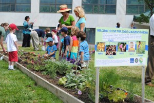 garden sign with children and adults at planting box