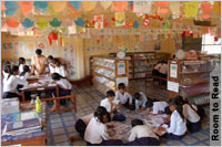 Group of children in library, reading at table and on floor (Room to Read )