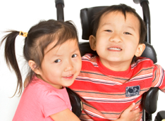 Young girl hugs boy in wheelchair