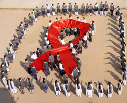 Photo of students holding up a red ribbon banner to promote AIDS awareness. 