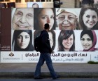 A Jordanian pedestrian passes by a Jordanian parliamentary campaign poster, in Amman