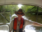 A man sitting on a boat with a vest and sunglasses