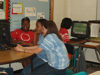 Two pc areas in a classroom with studnets doing group and individual work.