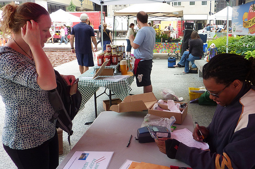 Corey Chapman, EBT Coordinator for City of Chicago farmers markets, processes a woman’s benefits card so she can purchase items at the market.