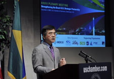 Locke on podium with plenary meeting banner behind him. Click for larger image.