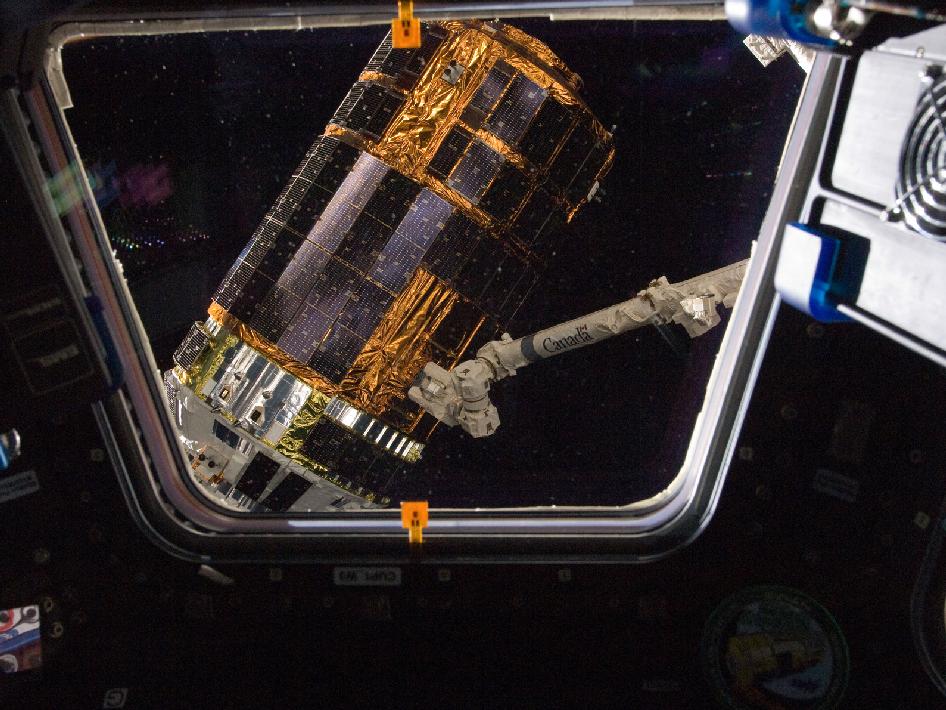 As seen through a window in the Cupola, the International Space Station’s Canadarm2 grapples the unpiloted Japan Aerospace Exploration Agency (JAXA) H-II Transfer Vehicle (HTV-3) (Photo: NASA)