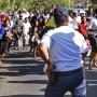 A police officer reaches for his weapon after crowds surge checkpoints trying to get a look at the body of leader Nelson Mandela.