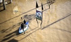 Two Palestinian men make their was along a flooded street in Gaza City