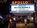 A newscaster broadcasts from under the marquee at the historic Apollo Theater, which announces the death of former South African President and civil rights champion Nelson Mandela, on December 5, 2013.  (Photo by Andrew Burton/Getty Images)