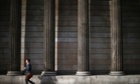 A man walks past the columns of the Bank of England in the city of London.