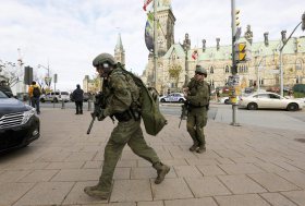 Armed RCMP officers head towards the Langevin Block on Parliament Hilll following a shooting incident in Ottawa on Oct. 22, 2014.