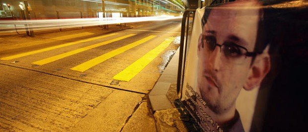 A bus passes by a poster of Edward Snowden, a former contractor at the NSA displayed by his supporters at Hong Kong's financial Central district