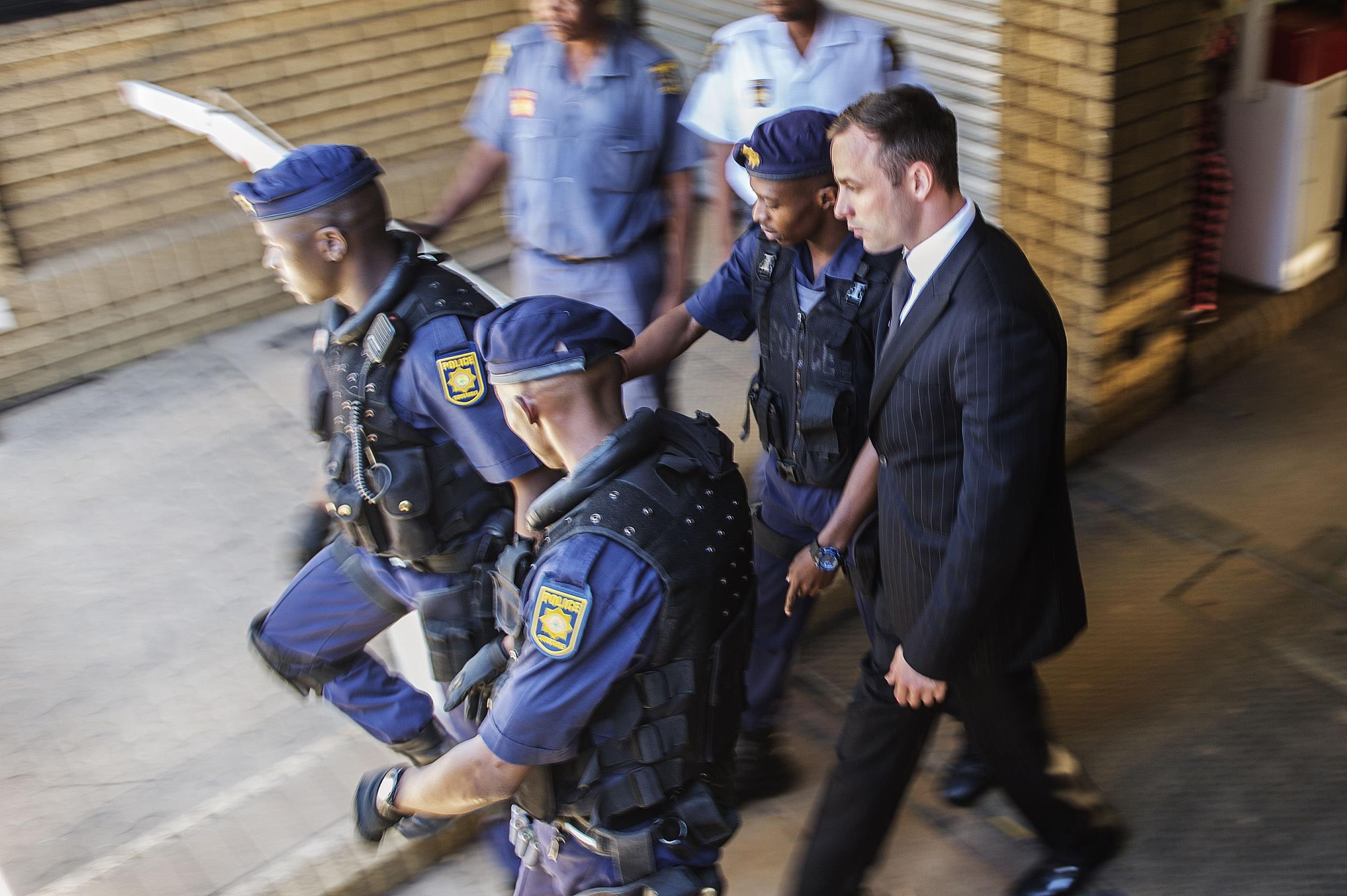 Image: Oscar Pistorius is escorted by South African policemen to a police vehicle to be transported to prison