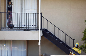 Neighboring people watch a man in a hazardous material suit work on cleaning the apartment unit where a man diagnosed with the Ebola virus was staying in Dallas