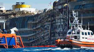 A Coast Guard patrols in front of the severely damaged right side of the Costa Concordia cruise ship after it was righted last week.