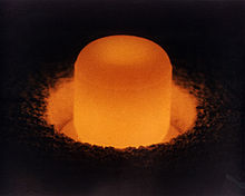 A glowing cylinder standing in a circular pit.