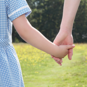 Young school girl holding mother's hand, close-up