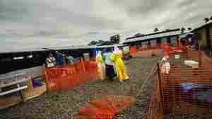 Nurses assist a new patient at an Ebola center in Liberia's Lofa County. As drug trials get underway, patients may receive experimental medicines.