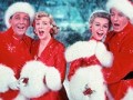 Bing Crosby, Rosemary Clooney, Vera-Ellen and Danny Kaye  sing together, while dressed in fur-trimmed red outfits and standing in front of a stage backrop, in a scene from the film 'White Christmas,'