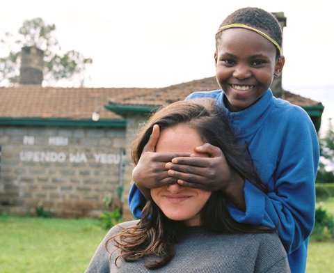 A young girl covers the eyes of a volunteer at Flying Kites in the Aberdares Mountains in Kenya.