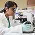 A researcher looking through a microscope.