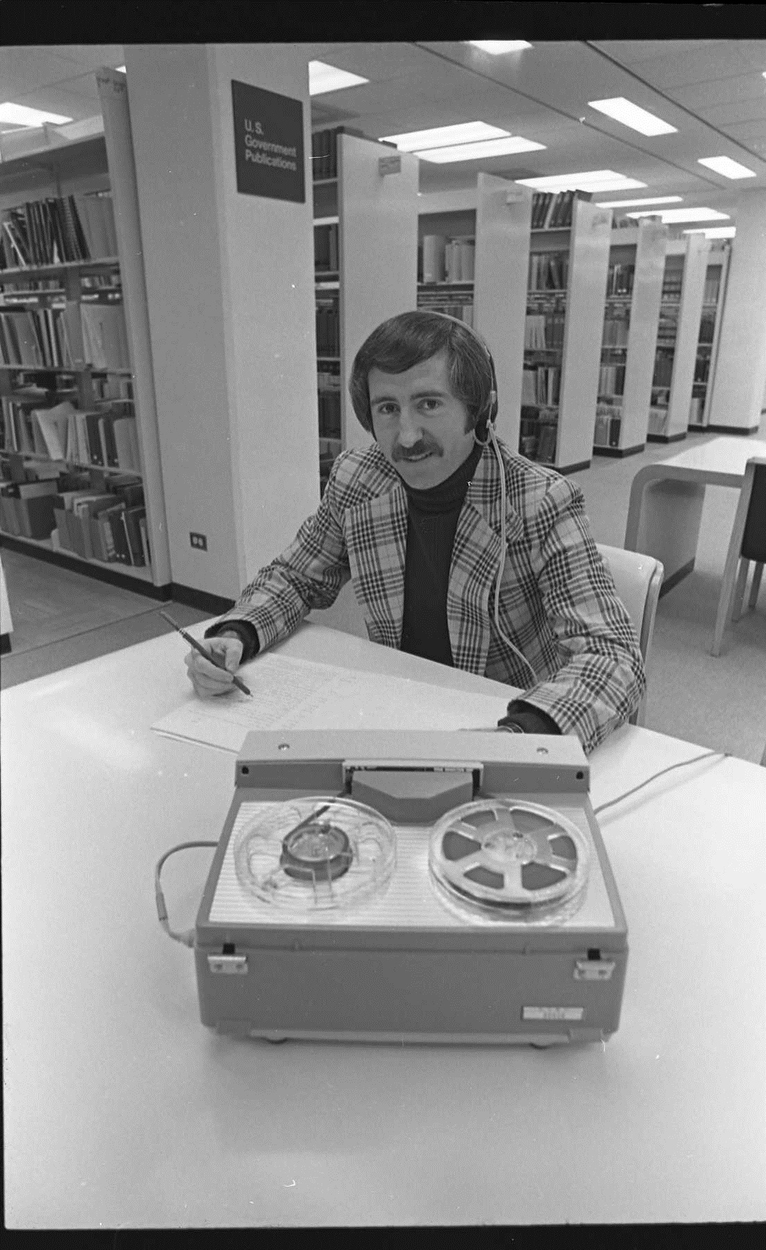 UNTA_UO458-147-4748-01 Dr. Ronald Marcello, a UNT History professor who was in charge of the Oral History Program from 1968 to 2005 at a table on the third floor of Willis Library demonstrating the use of the reel to reel recording equipment in January of 1975.