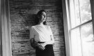 A young Eudora Welty standing against a wall.